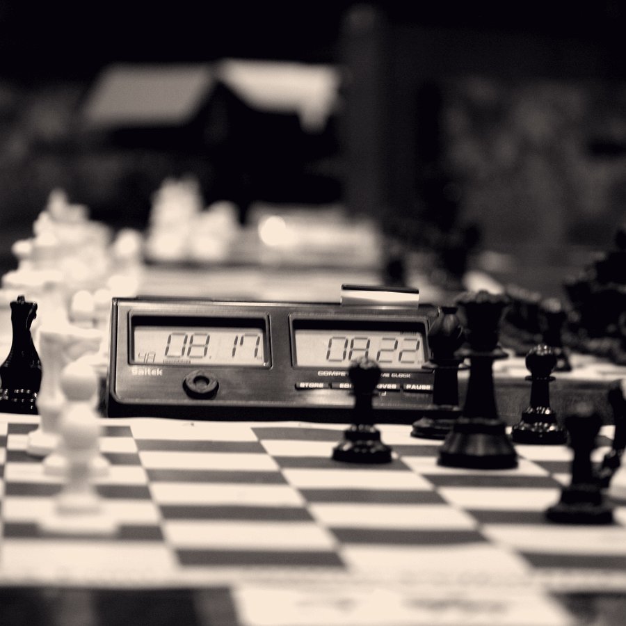A clock and a dense middlegame position in a tournament hall.