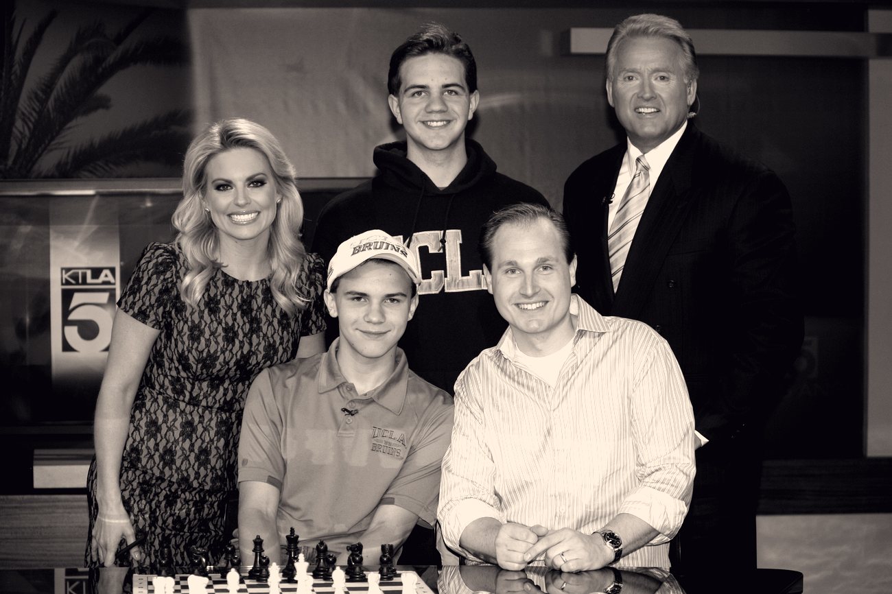 Daniel Vellotti with his sons Luke and Carl in the KTLA 5 studio, a chess board set up in front of them.